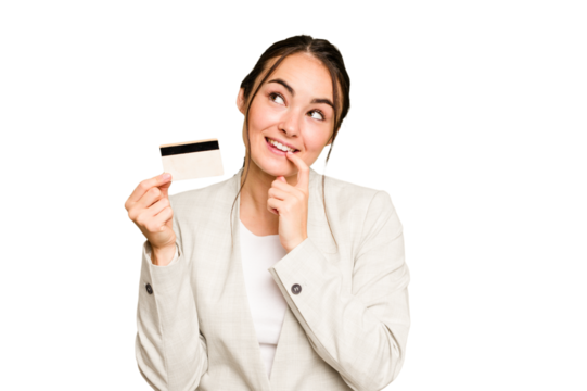 Young caucasian woman holding a credit card isolated on green chroma background relaxed thinking about something looking at a copy space.