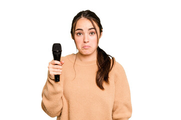 Young caucasian singer woman isolated on green chroma background shrugs shoulders and open eyes confused.