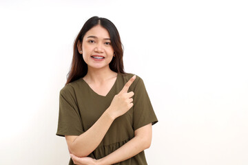 Portrait of beautiful young asian woman standing while pointing empty space. Isolated on white background