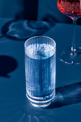 Transparent cocktail with gin and tonic on blue background with shadow. Gin tonic cocktail on...