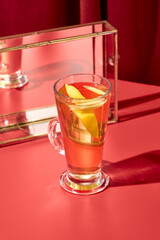 Alcohol hot drink from white wine and spices on red background. Winter beverage - gluhwein in minimal style. Winter drinks menu in trendy style with colour background. Hot cocktail in bar menu.