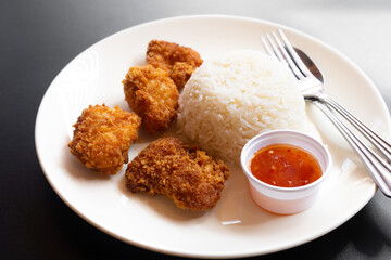 The dish of deep fried croquette and white jasmine rice and red dipping sauce with fork and spoon. 