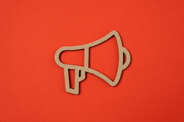 Paper cut cardboard megaphone on red background.