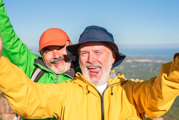 Happy funny elderly friends taking selfie while hiking together