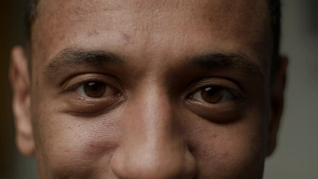 Black male eyes close up. African American man face smiling looking at camera.