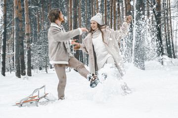Love romantic young couple girl,guy in snowy winter forest sledding,playing.Walking with sleigh in...
