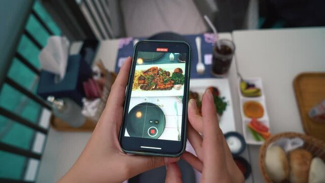  Blogger Woman Taking Photo of Food meat plate Using Mobile Phone in Restaurant. Flatlay Food Porn Concept on Wooden Table outside rest. Dubai, UAE. High quality 4k footage