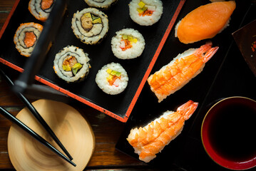 Sushi Set nigiri shrimp and salmon and sushi california rolls with avocado and maki with carrot, on wood,top view