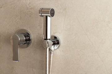 Stainless steel manual bidet sprayer located on the toilet wall