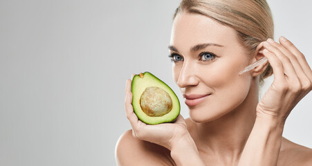 Caucasian woman applying avocado oil on her face with pipette dropper for nourishing and...