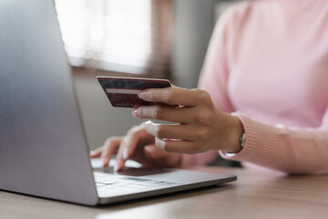 Young person using credit card and laptop computer. Online shopping, e-commerce concept