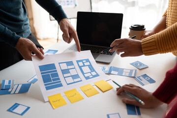 Ux developer and ui designer brainstorming about mobile app interface wireframe design on table...