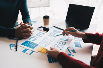 Ux developer and ui designer brainstorming about mobile app interface wireframe design on table...