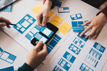 Ux developer and ui designer brainstorming about mobile app interface wireframe design on table...