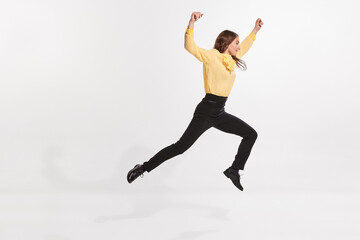Portrait of young woman jumping, moving forwards isolated over white studio background. Growing professional ambitions