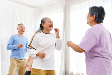 Active Asian senior group mix with man and woman exercise by dancing together with relaxing, smiling and laughing. Indoor activity for mature seniors and retirement people. Focus on senior woman.