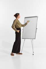 Portrait of young woman, manager, team leader writing tasks on flipchart isolated over white background