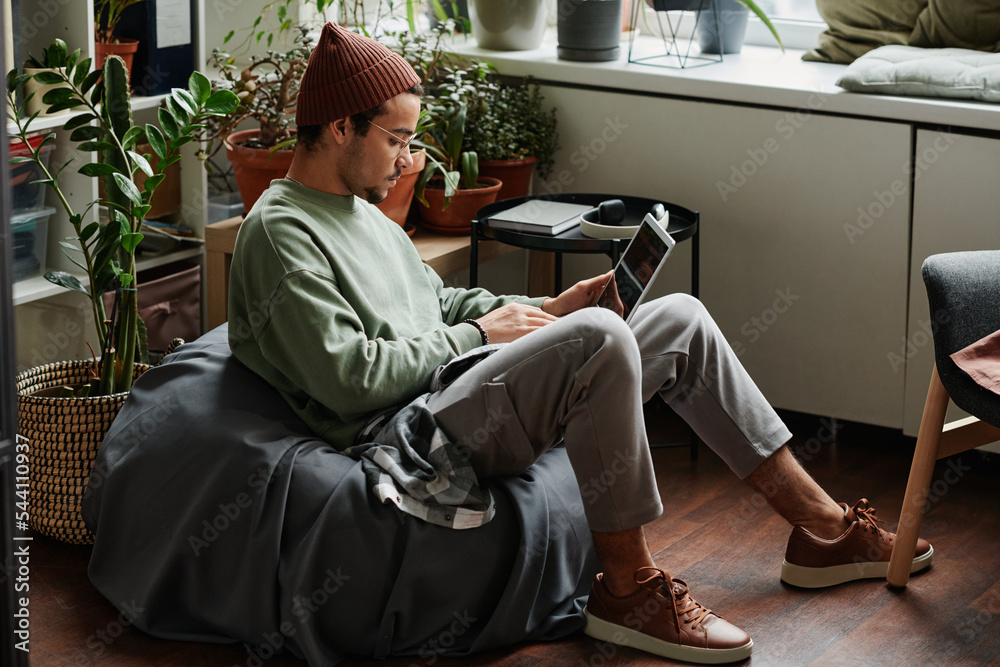 Aufkleber young serious webdesigner with laptop concentrating on network while sitting in comfortable armchair