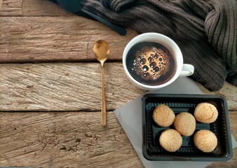 cup of coffee, spoon and cookies on wood background