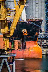 Port crane on the background of a large ship in the port	
