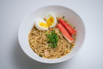 Home cook Japanese chicken soup instant noodle with egg, crab stick and scallion in white plates and isolated white background