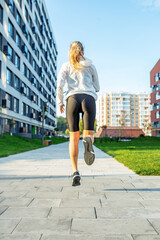 Sporty young woman running on sidewalk in morning. Concept of sport, healthy lifestyle and training.