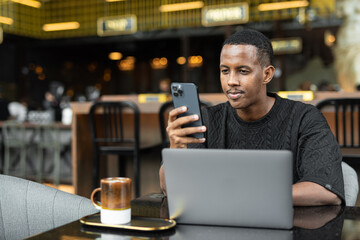 Portrait of handsome young African man using laptop computer in coffee shop - 544115330