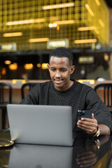 Portrait of handsome young African man using laptop computer in coffee shop - 544115352
