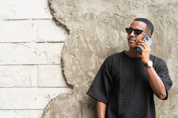 Portrait of handsome young African man using mobile phone outdoors