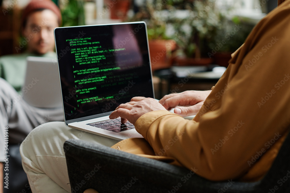 Fototapete Mature professional IT engineer developing new software or decoding data on laptop scren while typing in front of young coworker