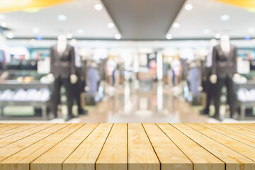 Empty wood table top with blur clothing boutique display interior shopping mall background