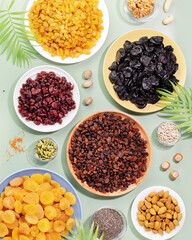 Dry fruits, nuts and seeds assortment on a blue background with palm leaves. Healthy snack - mix of organic nuts and dry fruits. Vegan and vegetarian products. Flat lay