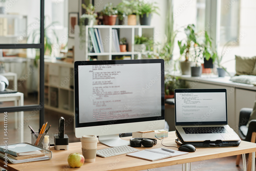 Poster Workplace of modern IT support engineer with computer monitor and laptop with coded data on screens in openspace office
