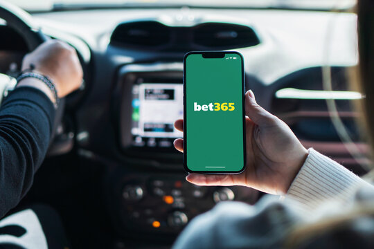 Girl inside car holding smartphone with Bet365 betting provider app on screen. Rio de Janeiro, RJ, Brazil. November 2022