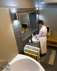 Young woman in white bathrobe washing hands in the bathroom