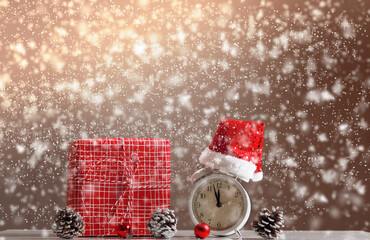 Merry Christmas. Gift box and alarm clock with defocused snowfall.