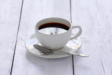Coffee cup with spoon on white wooden table