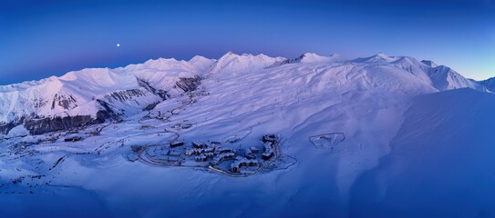 Wide aerial panorama of snowy mountain ridge on winter sunrise. Stunning mountains range covered...