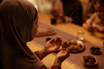 Close up of Middle Eastern woman during family prayer at dining table.