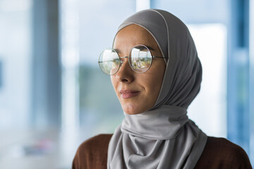 Close-up photo portrait of Muslim business woman wearing hijab and glasses, office worker looking...