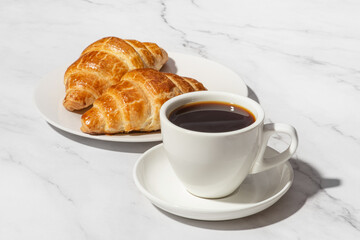 Paper cup of coffee with croissant on white background