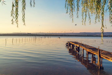 Sunset over the sea lake and old wooden pier, romantic travel destination, nature landscape 