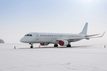 Fototapeta na wymiar White passenger airplane on the airport apron in a blizzard