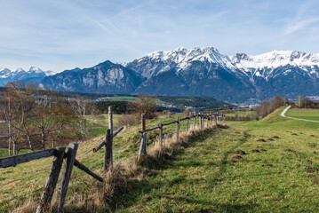 Fototapeta premium Landschaftsidyll mit Holzzaun und Schnee auf den Bergen