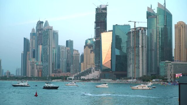 Panorama of modern skyscrapers in Dubai city with boats from the Blue waters Island. Dubai, United Arab Emirates. Dubai marina and JBR insunset. High quality 4k footage