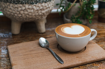 Hot coffee in white cup with coffee spoon on wooden tray. Copy space