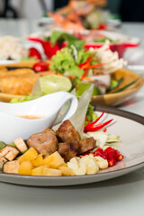 Close up of Namnueng with sliced banana pine apple chilli and dipped sauce with row of various Vietnamese food as background
