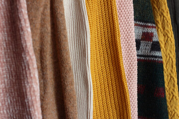 Warm clothes. Women's jumpers and cardigans in different colors, clothes on hangers in the store.