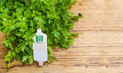 Fresh green parsley with bio label  on wooden background with copy space 