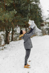 Family walking in the snow having fun in winter park on a bright day hugging each other and smiling